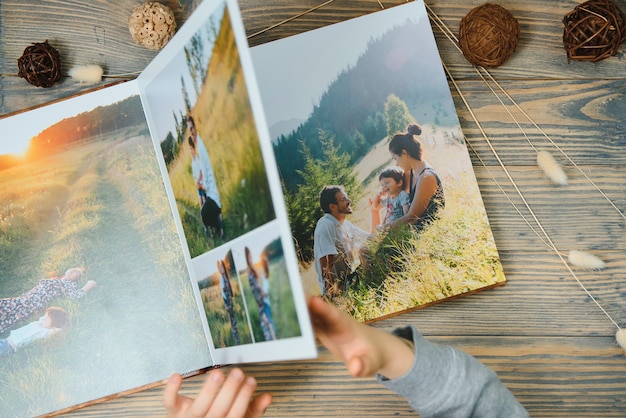 L'enfant tenant un album photo de famille sur une table en bois