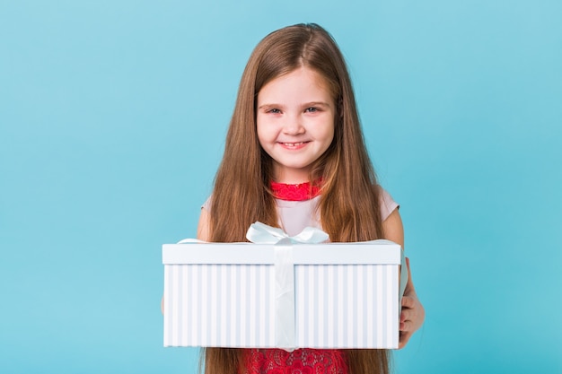 Enfant tenant des cadeaux d'anniversaire ou de Noël sur un bleu