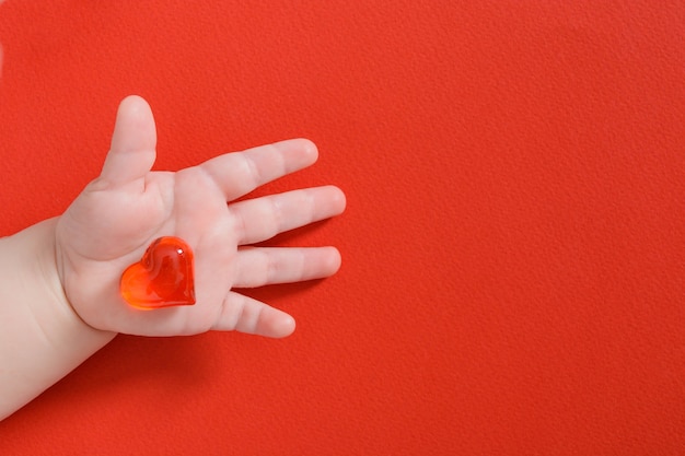 Enfant tenant coeur de verre isolé sur rouge