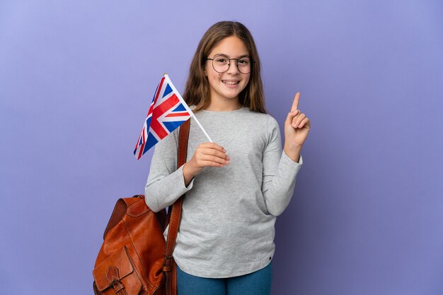 Enfant tenant un drapeau du Royaume-Uni sur fond isolé montrant et levant un doigt en signe du meilleur