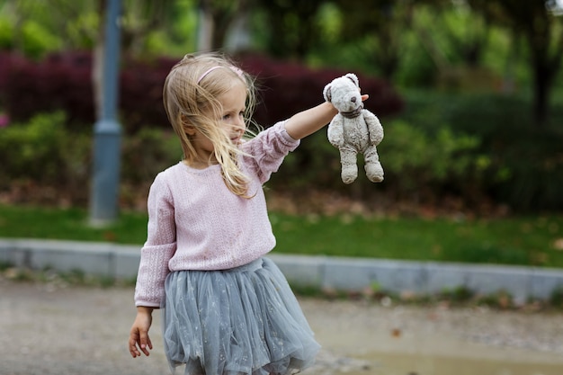 Enfant tenant un ours en peluche en plein air