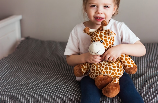 Enfant tenant une peluche girafe sur fond gris