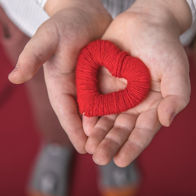 Enfant tenant un petit coeur rouge