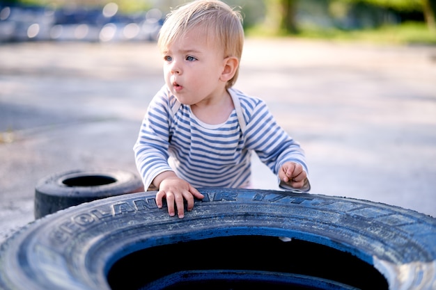 Enfant tenant un pneu de voiture dans un parking