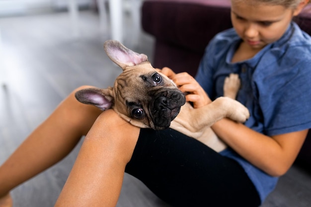 Enfant tenant son animal de compagnie fille assise avec un chiot bouledogue français