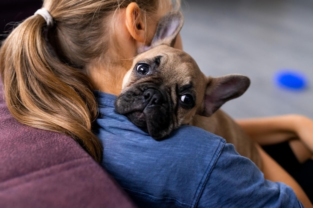 Enfant tenant son animal de compagnie fille assise avec un chiot bouledogue français