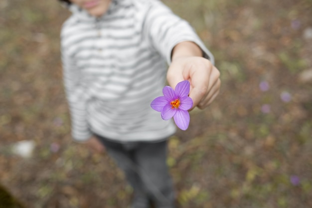 Photo l'enfant tend une fleur violette