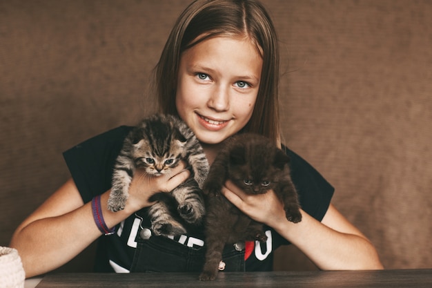 Un enfant tient de beaux chatons britanniques dans ses mains