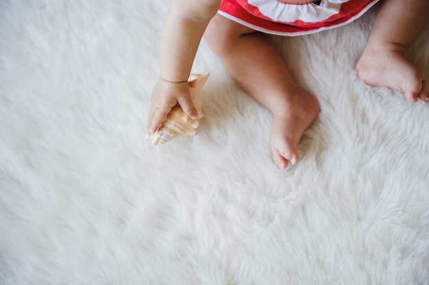 L'enfant tient un coquillage dans ses mains.