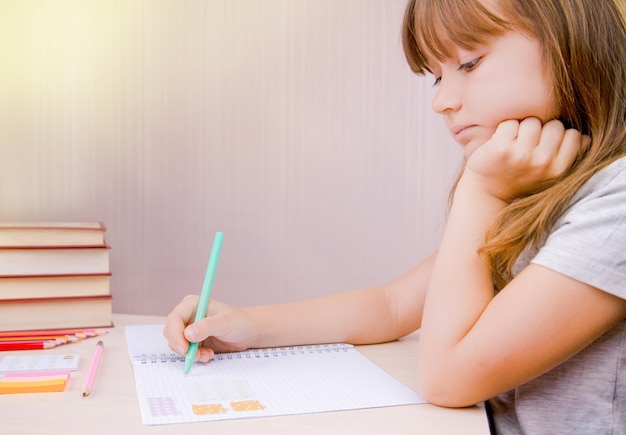 L'enfant tient un crayon dans ses mains Terminer ses devoirs scolaires