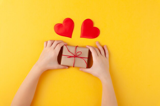 Enfant tient dans les mains boîte-cadeau surprise, de nombreux coeurs rouges, amour et concept de Saint Valentin