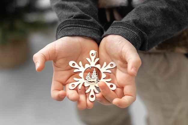 L'enfant tient dans ses mains un flocon de neige décoratif une étoile Décoration pour l'arbre de Noël