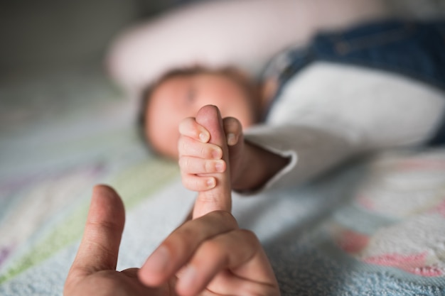 L'enfant tient le doigt. Main de bébé tenant doucement le doigt de l'adulte.