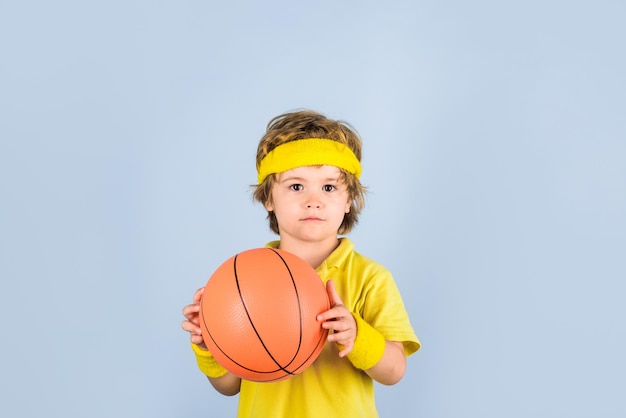 L'enfant tient un enfant de basket-ball jouant avec un garçon de basket-ball dans un garçon sportif de vêtements de sport avec un sport de balle