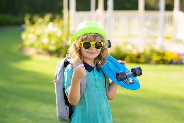 Un enfant tient une planche à roulettes lors d'une journée ensoleillée dans le parc portrait en plein air d'un petit concept de skateur