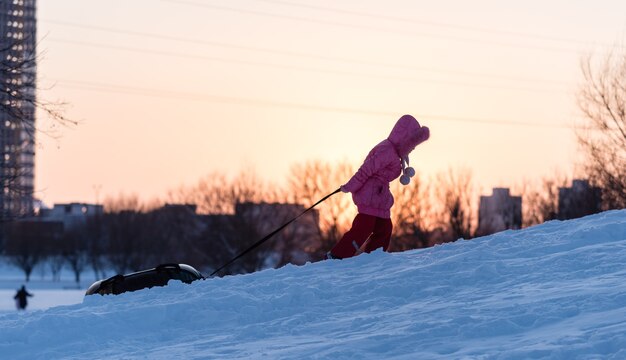 Un enfant tire un tube sur une montagne enneigée au coucher du soleil