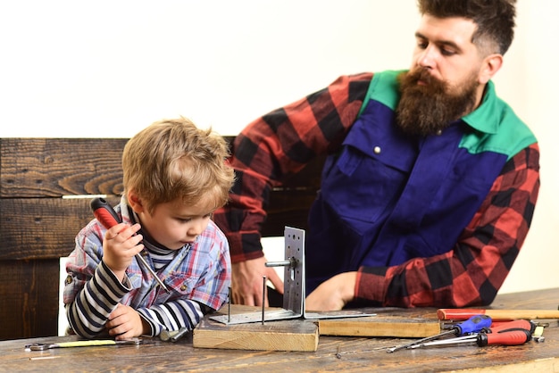 Enfant avec tournevis jouant en artisan. Paternité, réparation, concept d'assistance - papa apprend à son petit fils à utiliser des outils. Garçon concentré avec père réparant ensemble. Garçon mignon explorant de nouvelles choses.