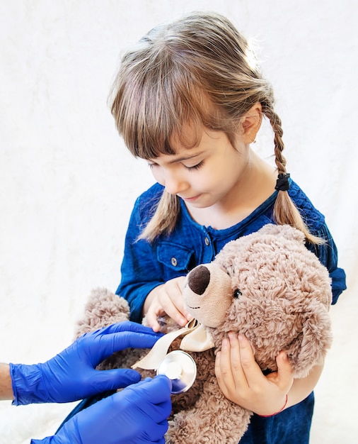 Enfant traite un ours. Le jeu du docteur. Mise au point sélective.