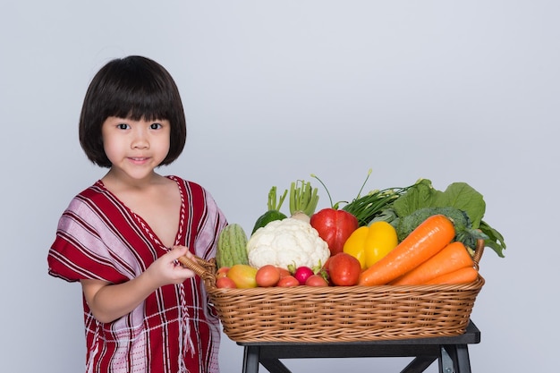 enfant transportant des légumes sur fond gris