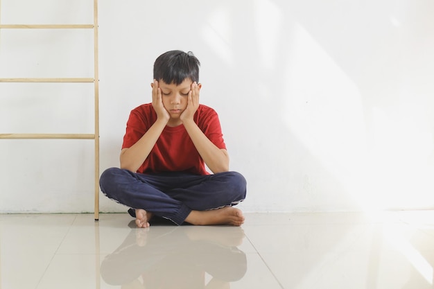 Enfant triste et solitaire assis sur le sol contre le mur Expérience traumatisante de l'enfance