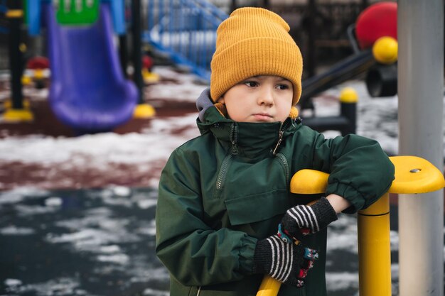 Un enfant triste et solitaire jouant seul dans le parc en hiver.