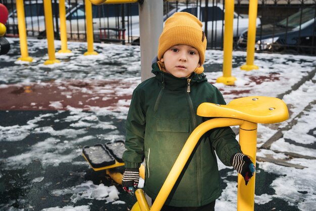 Un enfant triste et solitaire jouant seul dans le parc en hiver.