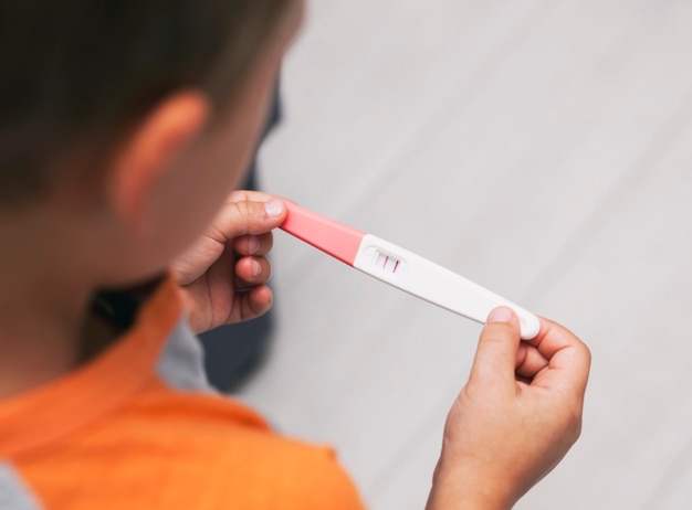 Photo l'enfant a trouvé le test de grossesse positif et l'a regardé sans savoir de quoi il s'agissait