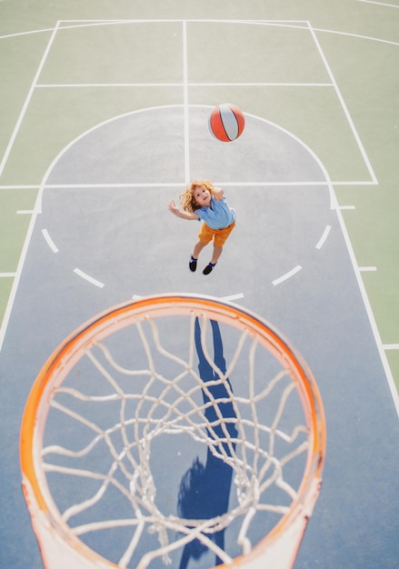 Enfant en uniforme de basket-ball sautant avec un ballon de basket pour un tir sur un terrain de basket