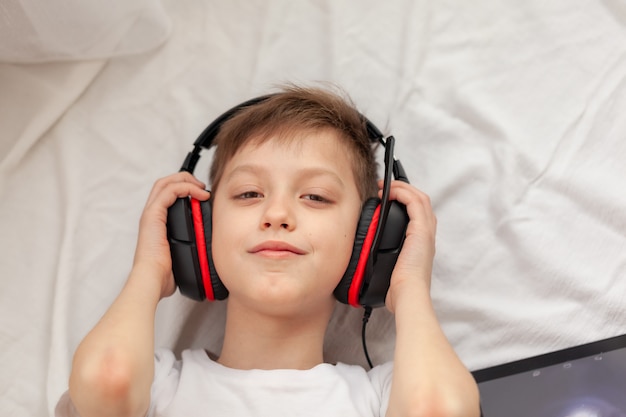 Enfant Utilisant Une Tablette Numérique Et Un Ordinateur Portable En écoutant De La Musique Sur Le Tapis à La Maison. éducation Conceptuelle En Ligne