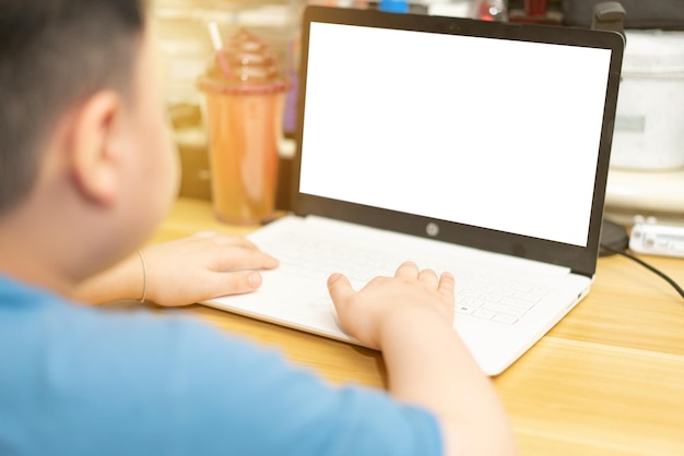 Un enfant utilise un ordinateur sur une table à la maison