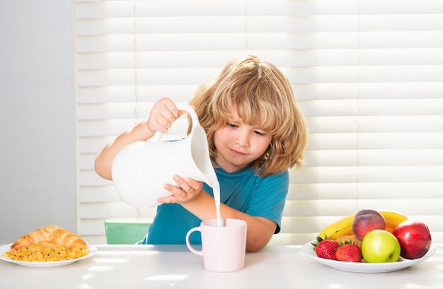 Enfant versant du lait de vache entier écolier mangeant le petit déjeuner avant l'école portrait d'un petit adolescent