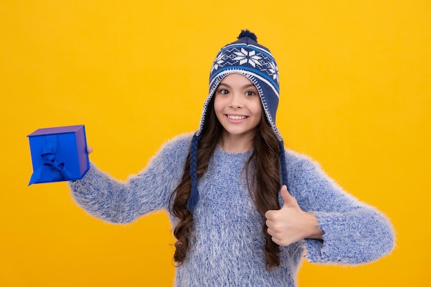 Enfant en vêtements d'hiver tenant un cadeau pour le Nouvel An ou Noël Visage heureux émotions positives et souriantes d'une adolescente