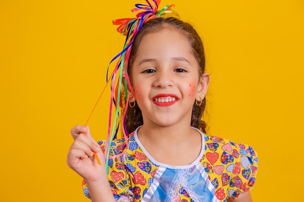 Enfant en vêtements typiques de la célèbre fête brésilienne appelée Festa Junina en célébration de Sao Joao Belle fille sur fond jaunexA