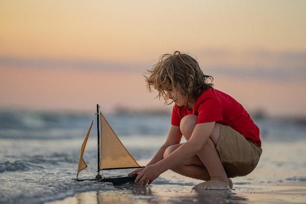 Enfant voyageant sur la mer enfant garçon jouant avec un bateau jouet dans l'eau de mer joyeuses fêtes au bord de la mer kid dreamin