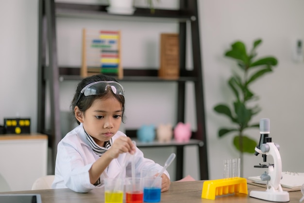 Photo enfante asiatique apprenant la chimie des sciences avec un tube à essai faisant des expériences à l'école laboratoire éducation des sciences chimie et concepts des enfants développement précoce des enfants