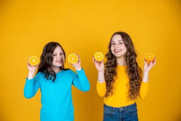 Les Enfants Adolescents Joyeux Tiennent Des Fruits Orange Sur Fond Jaune.