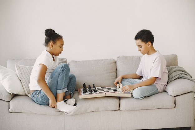 Enfants africains sur le canapé. Jeu d'échecs. Enfants aux cheveux bouclés.