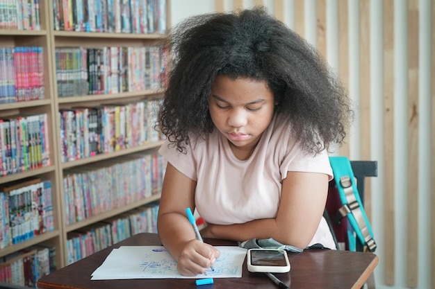 Enfants africains dessinant et faisant leurs devoirs en classe jeune fille heureuse étude drôle à l'école