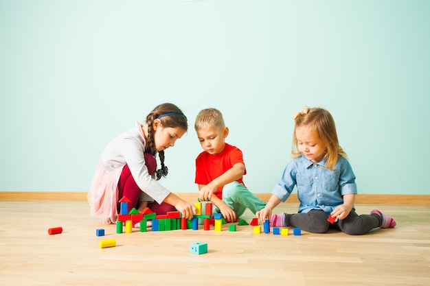 Les enfants d'âge préscolaire jouent ensemble en créant à partir des blocs de bois. Enfants jouant avec des blocs colorés apprenant à coopérer.