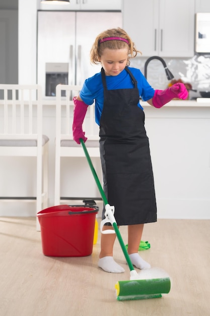 Enfants aidant au ménage à nettoyer la maison Ménage à la maison Mignon enfant garçon aidant au ménage sur le fond intérieur de la cuisine