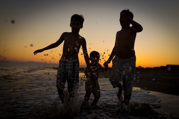 Enfants amusants jouant des éclaboussures à la plage