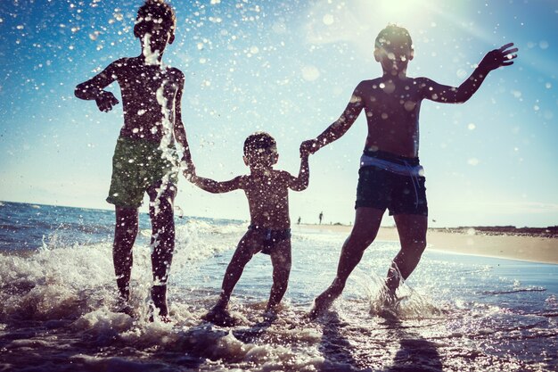 Enfants amusants jouant des éclaboussures à la plage