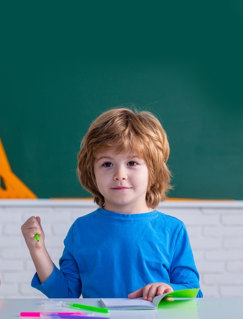 Enfants apprenant un garçon mignon dans une salle de classe près d'un bureau de tableau noir