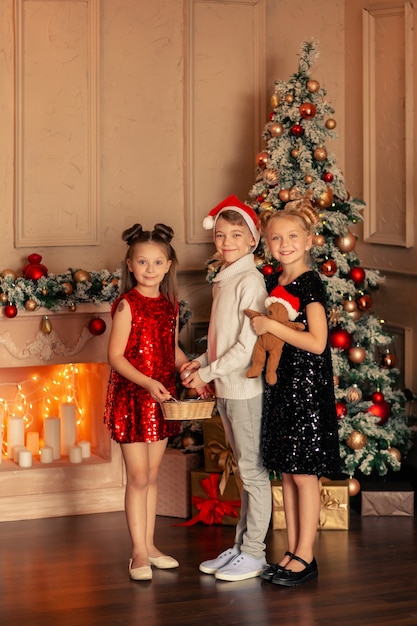 Enfants à l'arbre de Noël dans un intérieur festif