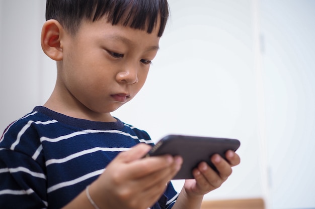Les enfants asiatiques à l'ère des réseaux sociaux qui se concentrent sur les téléphones ou les tablettes