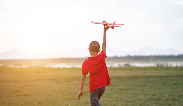 Enfants asiatiques jouant ensemble à l'avion en carton dans le parc à l'extérieur