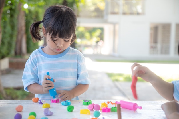 Les enfants asiatiques jouent avec des formes de moulage en argile, apprenant par le jeu