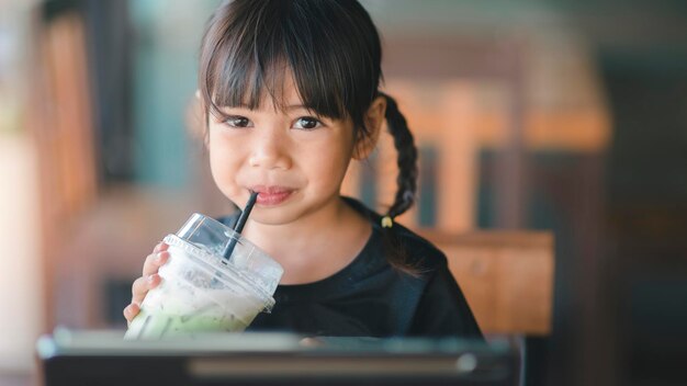 Enfants asiatiques mignons buvant du jus frais dans le café