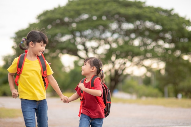 Enfants asiatiques mignons tenant la main ensemble en allant à l'école