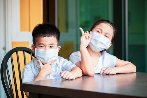 Les enfants asiatiques portant un masque de protection étudient à l'école à domicile